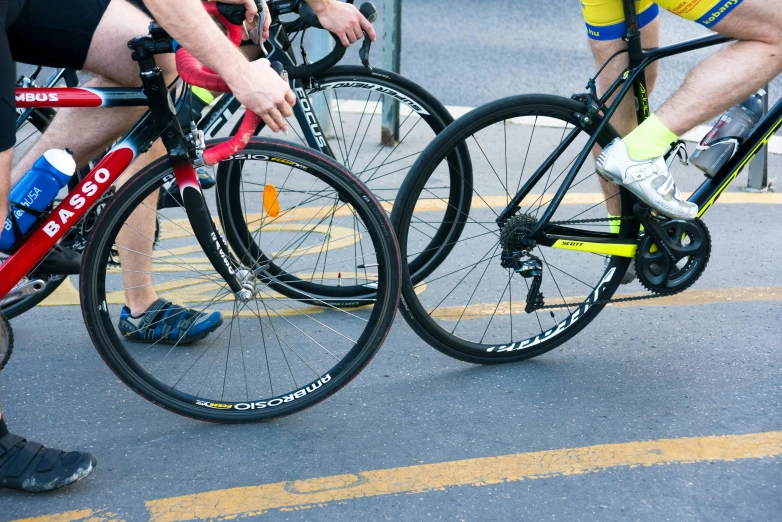 three cyclists are standing together on a road