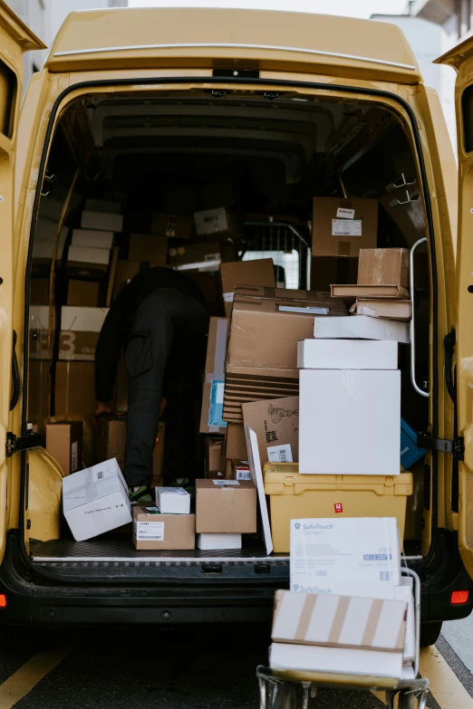 a man in black jacket reaching into the back of a van