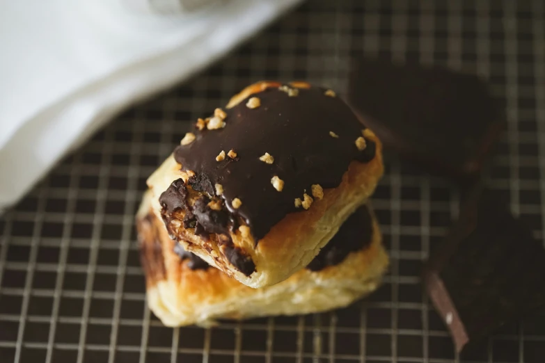 one  dog in a bun is wrapped with chocolate, and the other has nuts on it