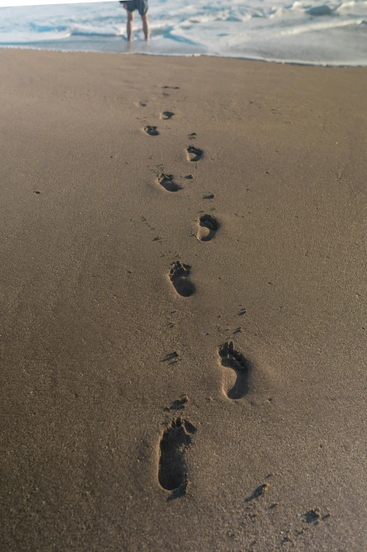 a person's feet in the sand by the ocean