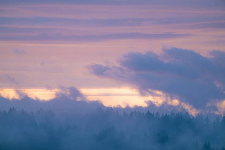 silhouettes of clouds are shown against a pink and blue sky