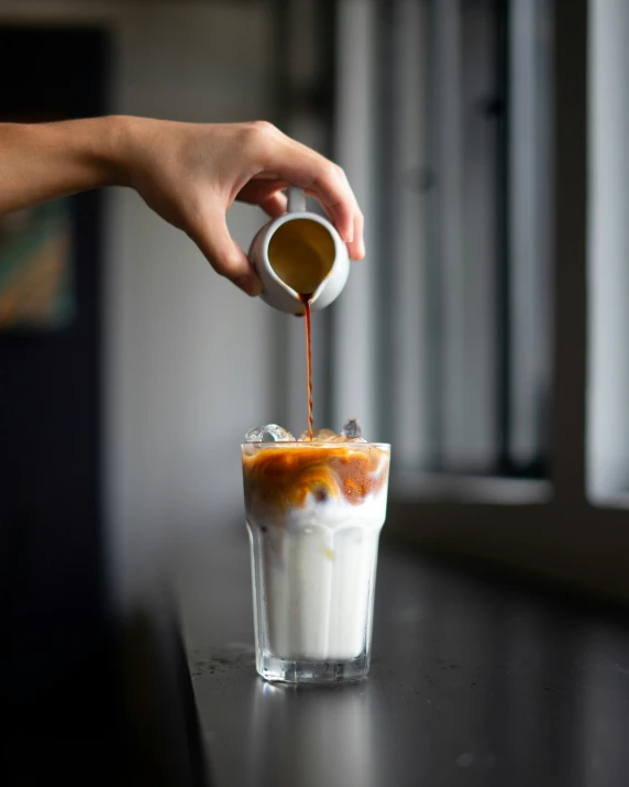 someone pouring soing into a glass with milk and ice