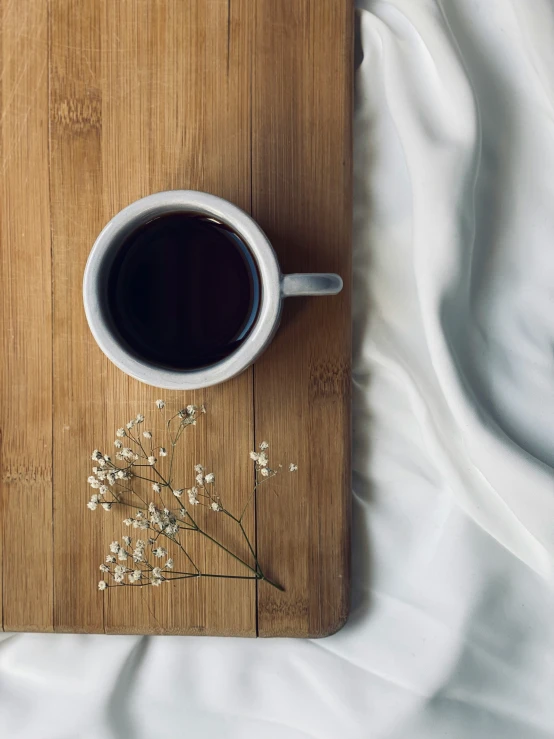 coffee, flowers, and blanket are lying next to each other