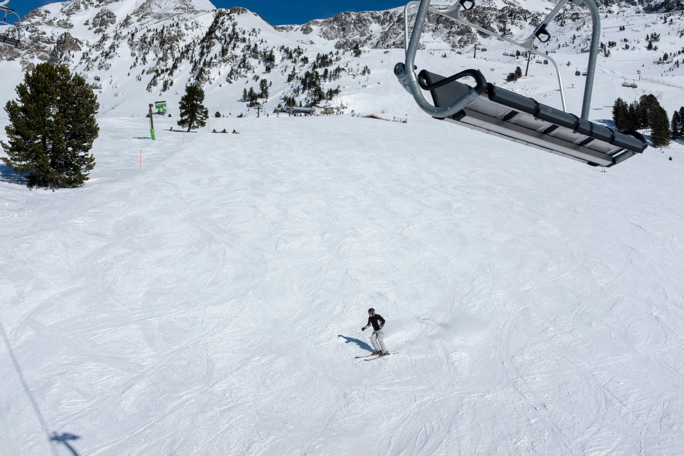 person on snowboard riding a slope near ski lift