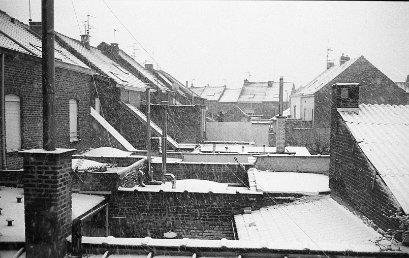 the roofs of some buildings in snow with power lines above them