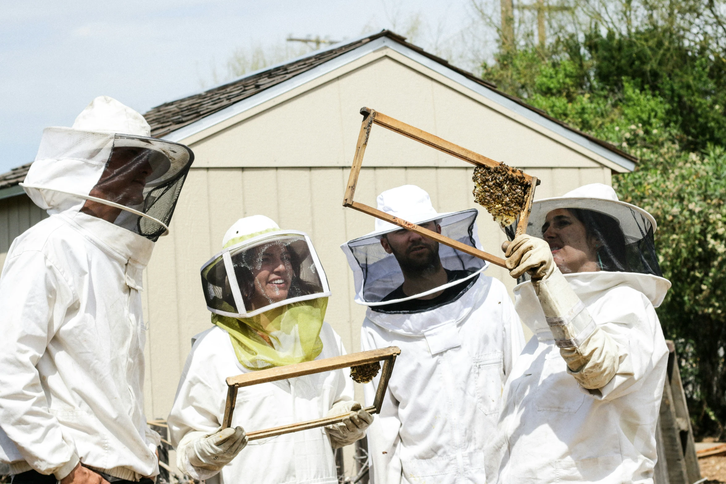 four people in bee suits with bee nets