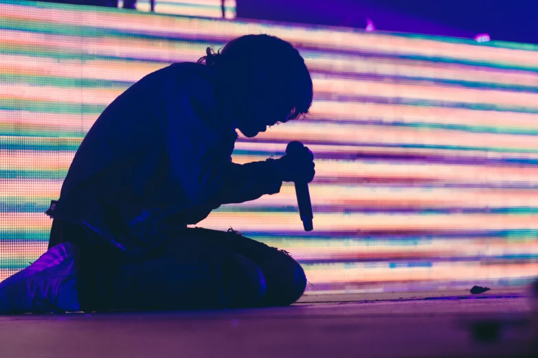 a young man sitting down while holding a microphone