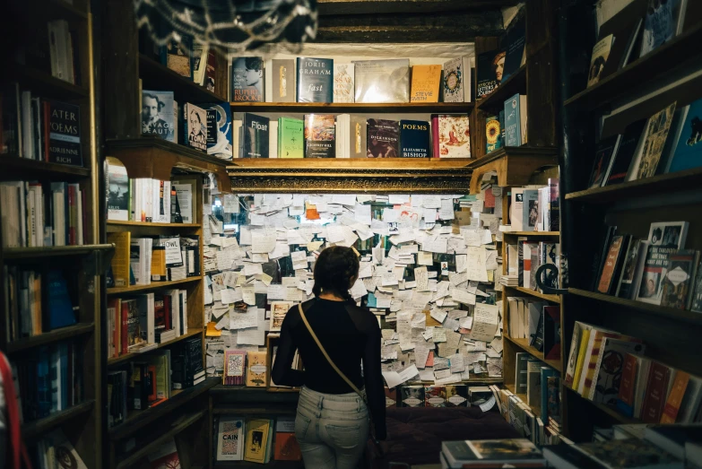 person reading in liry with books stacked up