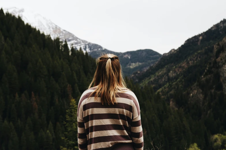 a woman with long hair standing at the base of a mountain