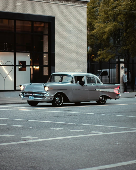 a grey car parked next to a street with people