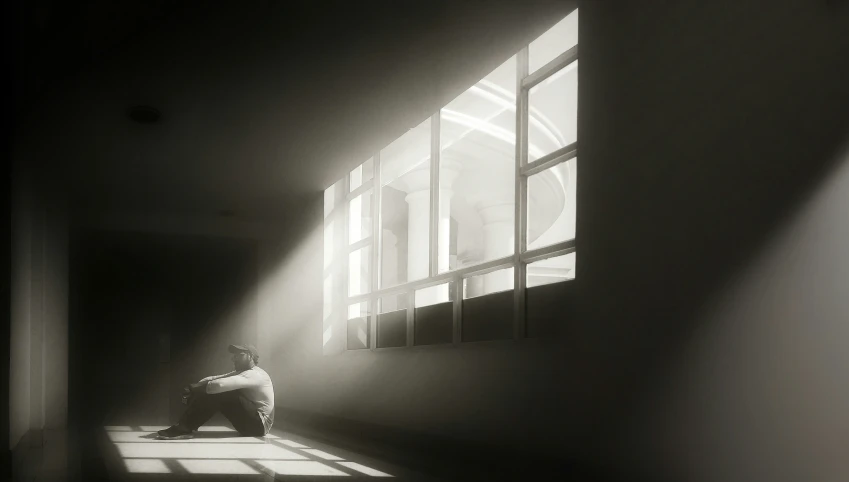 man sitting on a chair looking through an open window