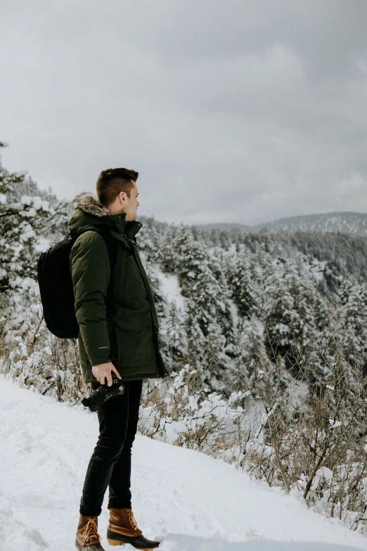 man with back pack and backpack standing on slope near snowy area