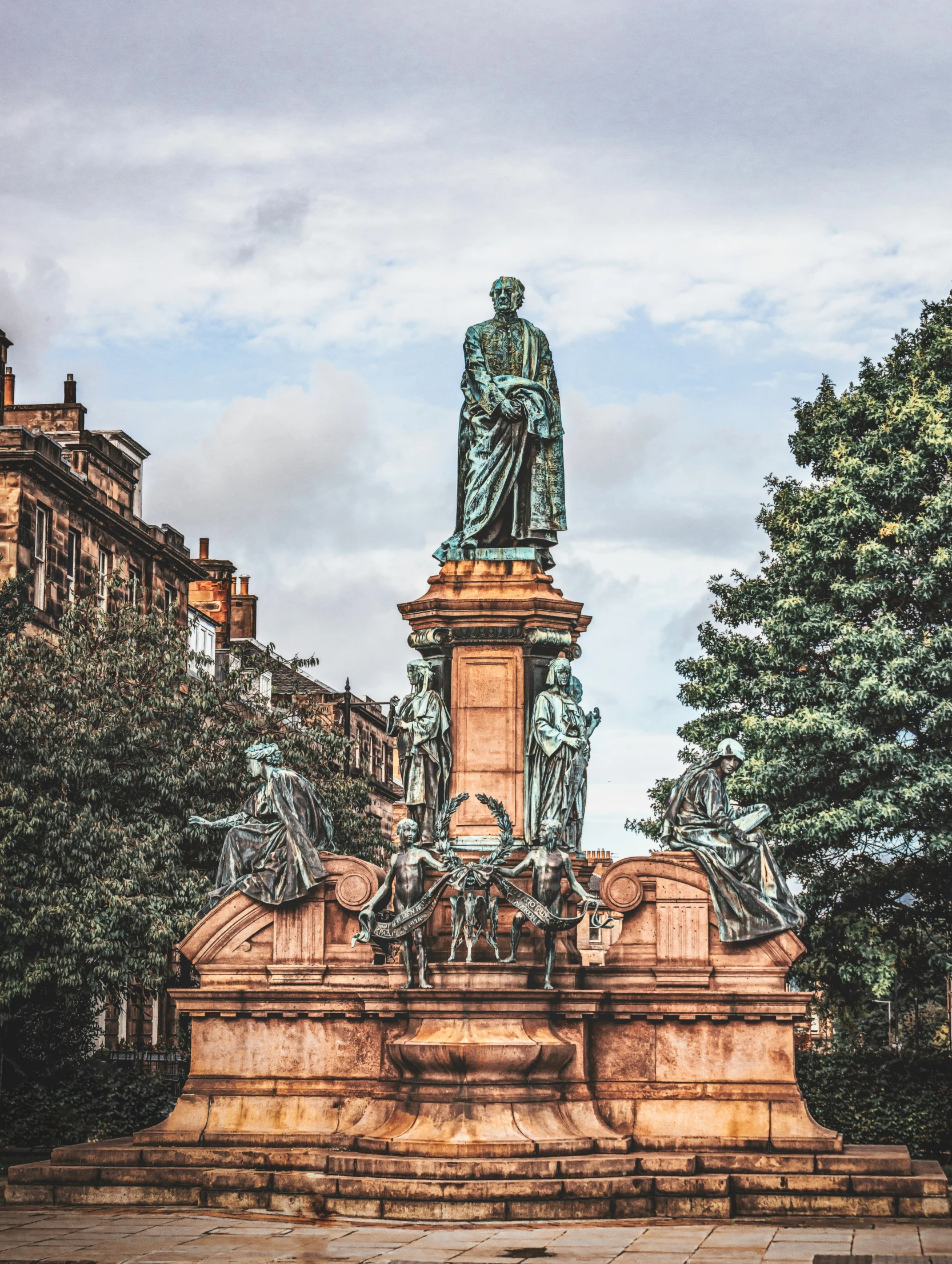 the statue is surrounded by trees and in the middle of a small city