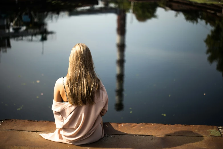 a person that is sitting down and looking at the water