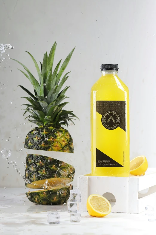 a bottle of yellow liquid next to a pineapple