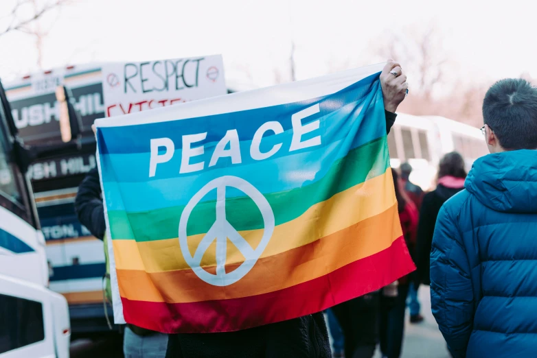 a man holding a flag while wearing a peace sign