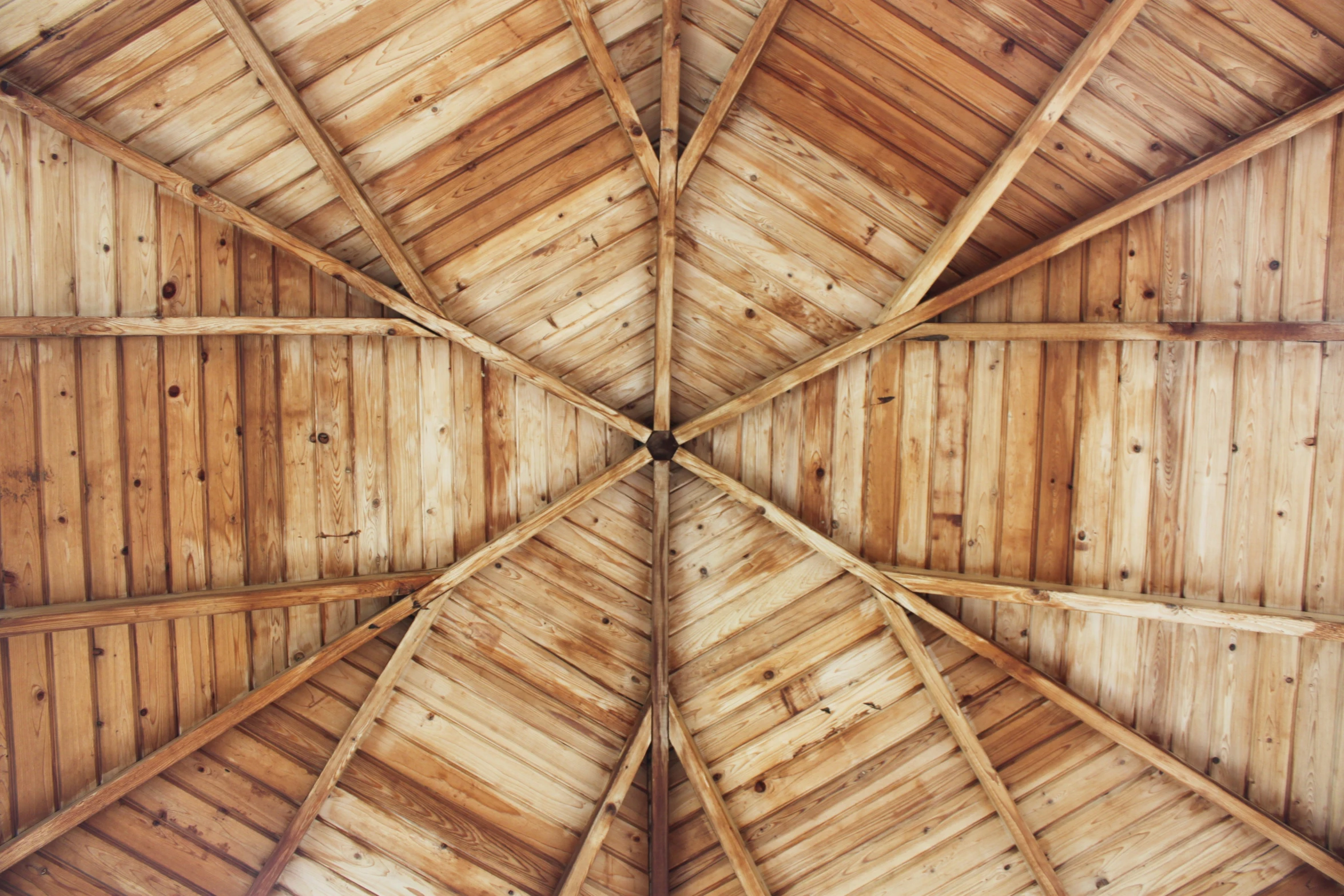 the underside view of a building's roof made out of wooden planks