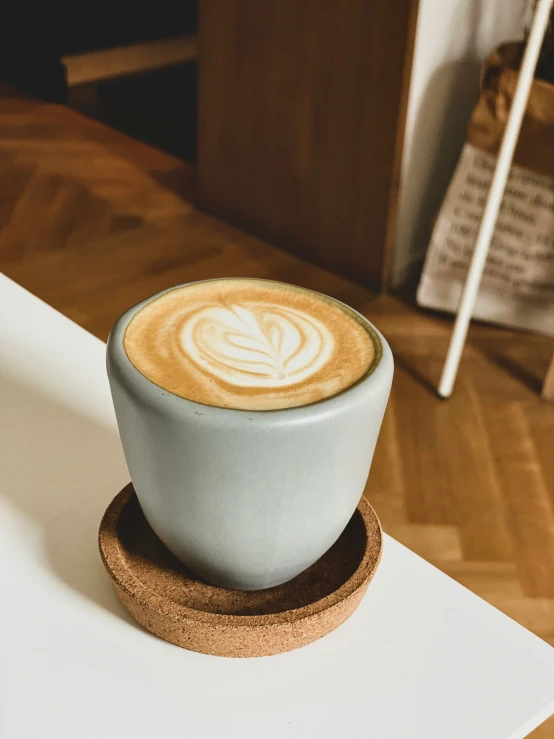 a white cup of coffee sitting on top of a plate