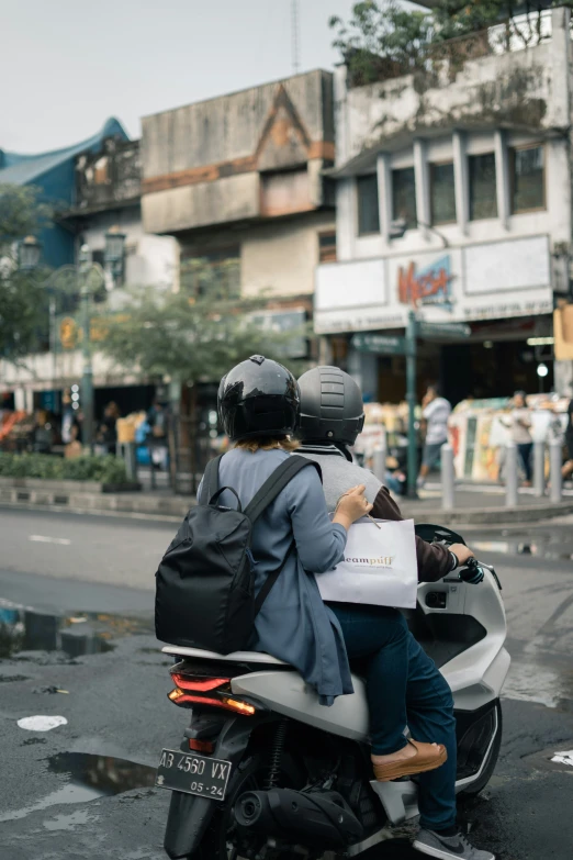 two people on a scooter with a backpack strapped to it