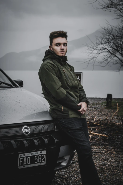 a man leans on the hood of his car