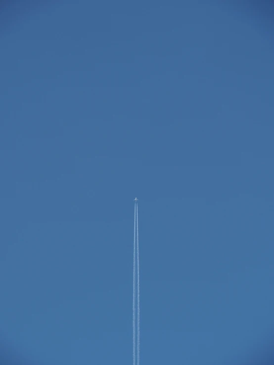 an airplane flying through the air with a line of smoke coming out