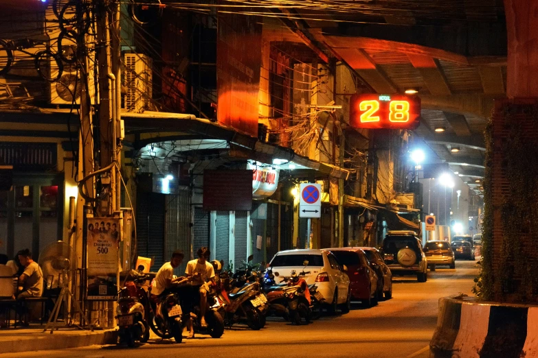 a city at night, with people sitting in the street