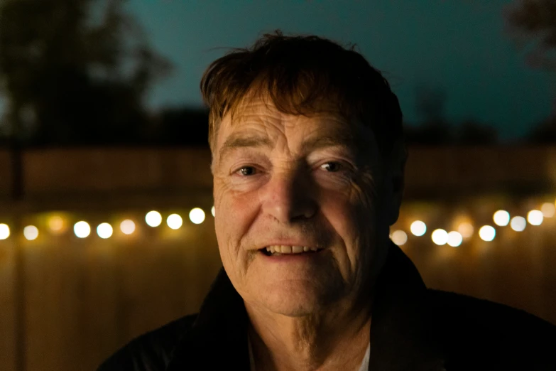 a man standing outside next to some light strings