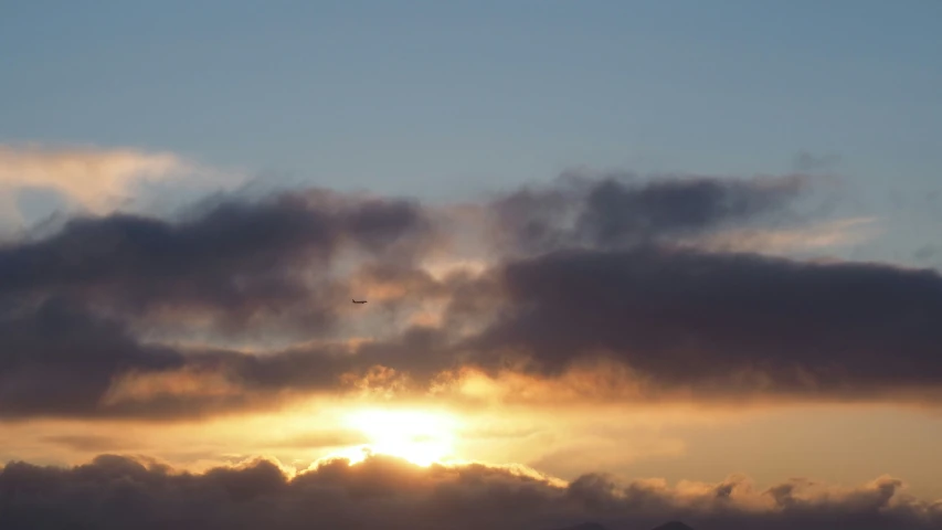 the airplane is flying low to the clouds as the sun sets