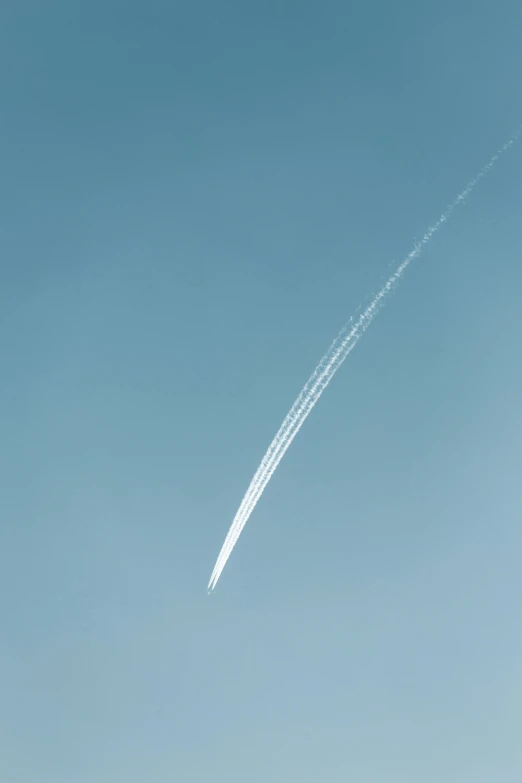 an airplane flying in a blue sky leaving a contrail