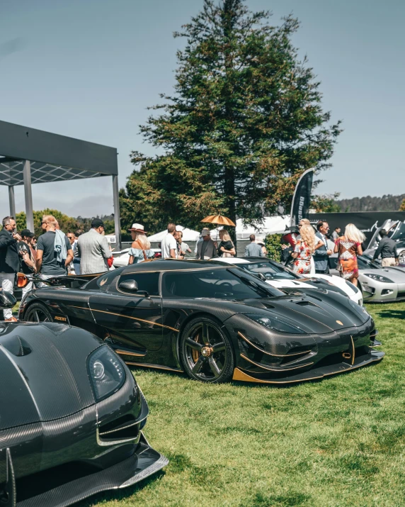 many people are standing by very nice looking sports cars