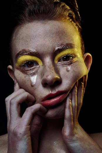 a woman with yellow makeup looks at the camera