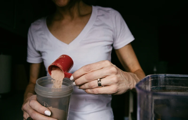 a woman is putting soing into a glass