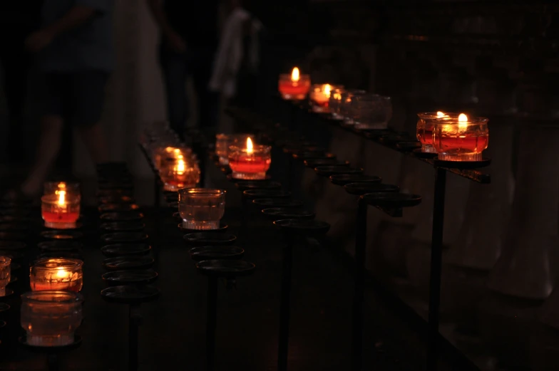 many lit candles are arranged on small stands