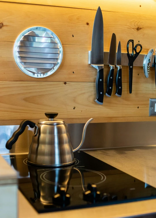 a tea kettle on the stove with knives on it