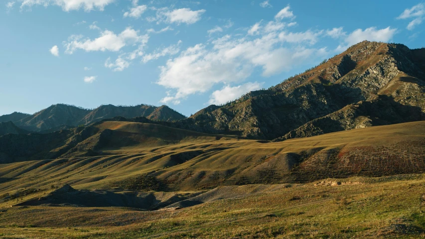 mountains are surrounding the grassy valley in the distance