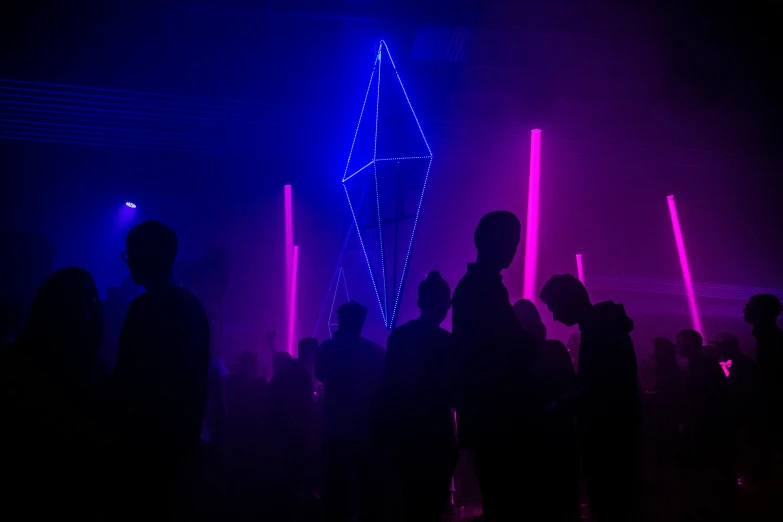 dark silhouettes of people dancing on stage in front of purple and blue lights