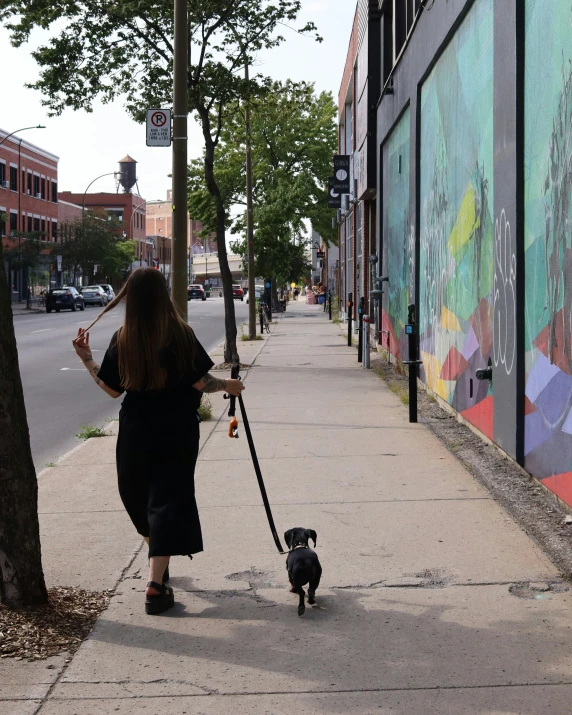 the woman is walking the dog on the sidewalk