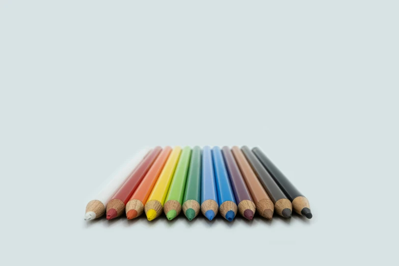 a rainbow of multicolored colored pencils laid out in a row