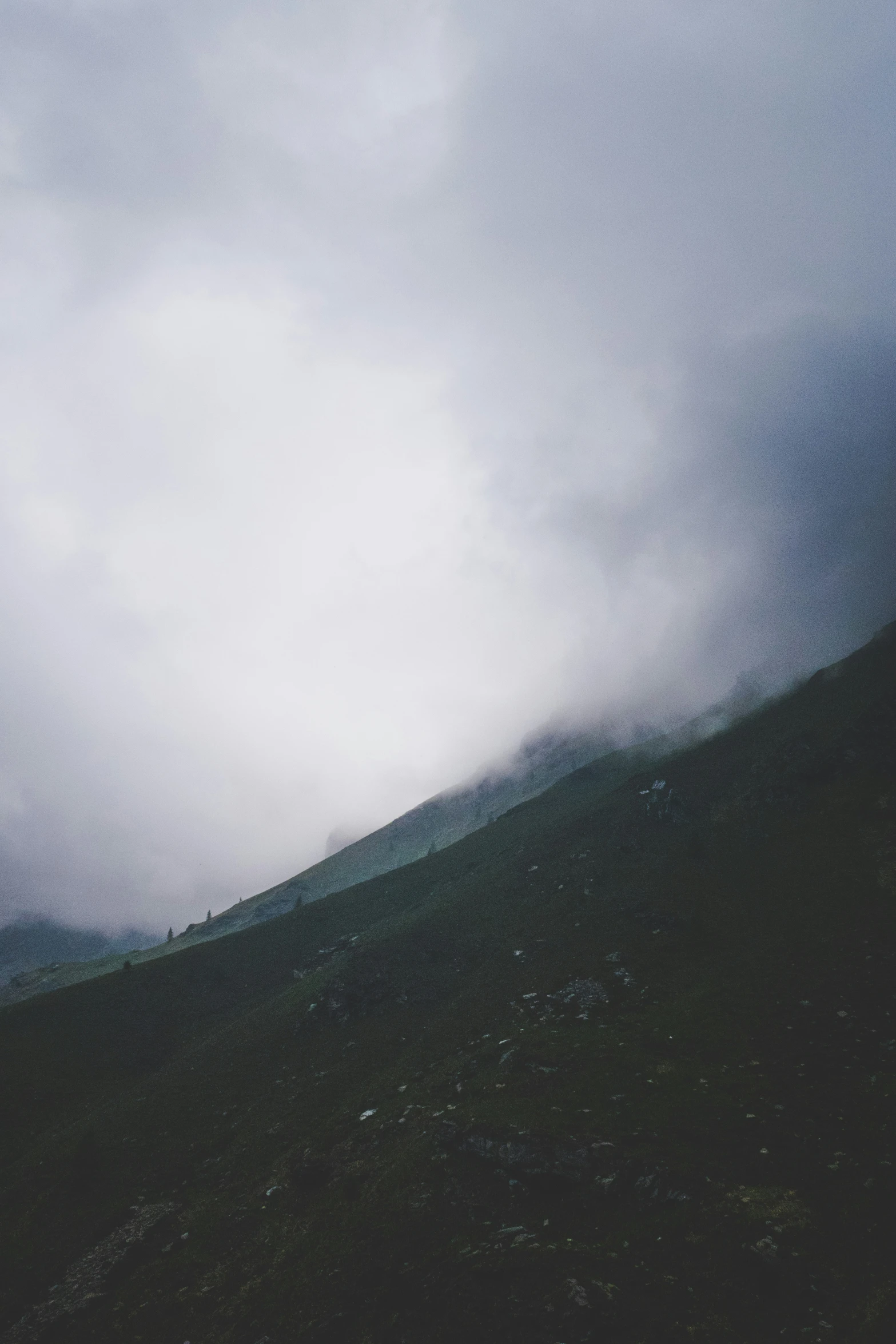 a mountain side with low flying clouds and fog