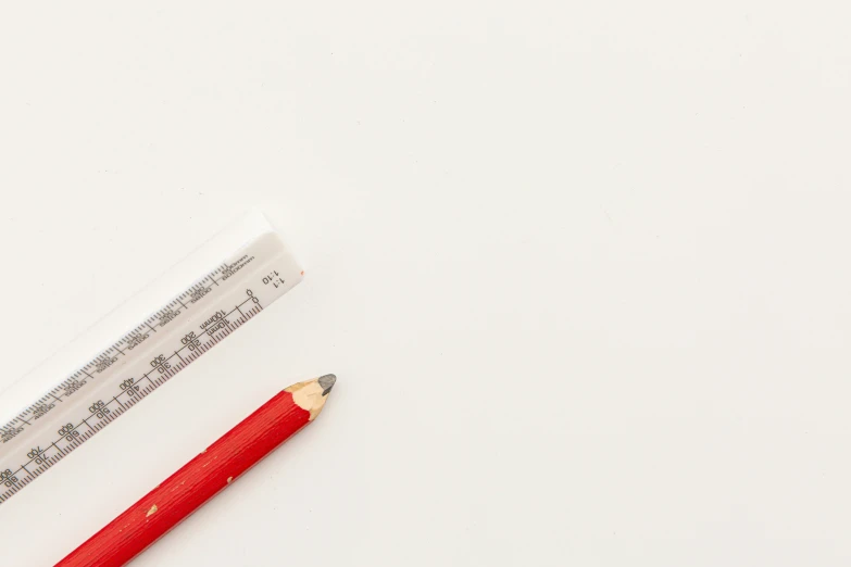 a red pencil and a ruler laying on the table