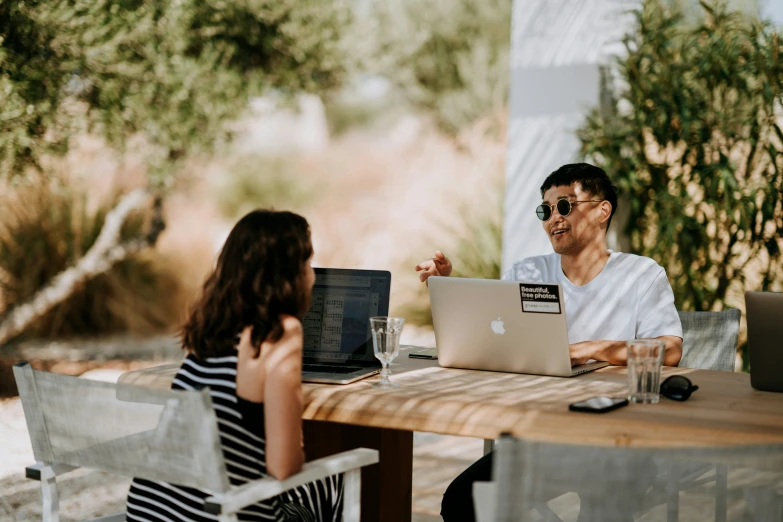 a man and woman are at a table with laptops