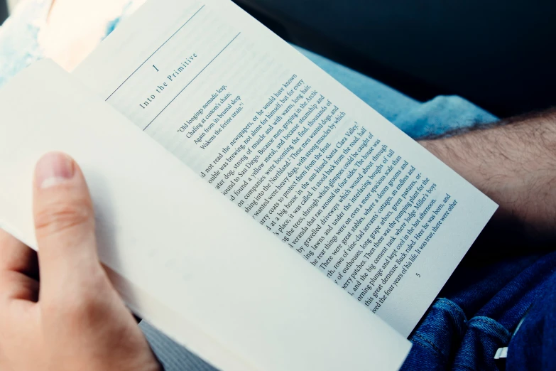 man reading a book while sitting down on the couch