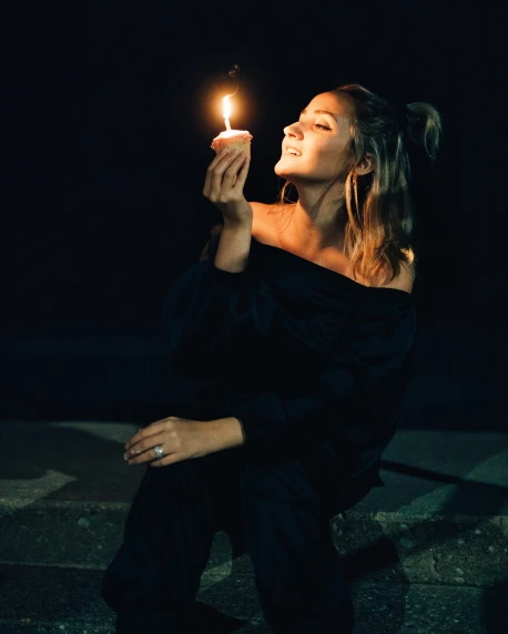 a woman sitting down holding a lit candle