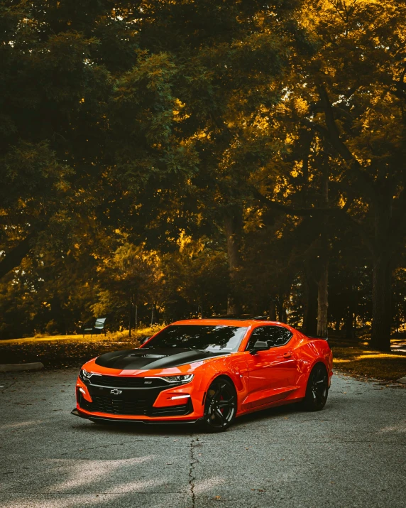 a small red car in a parking lot with trees in the background