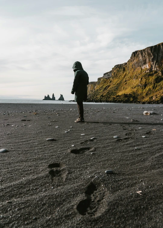 man walking on beach with mountains in the distance