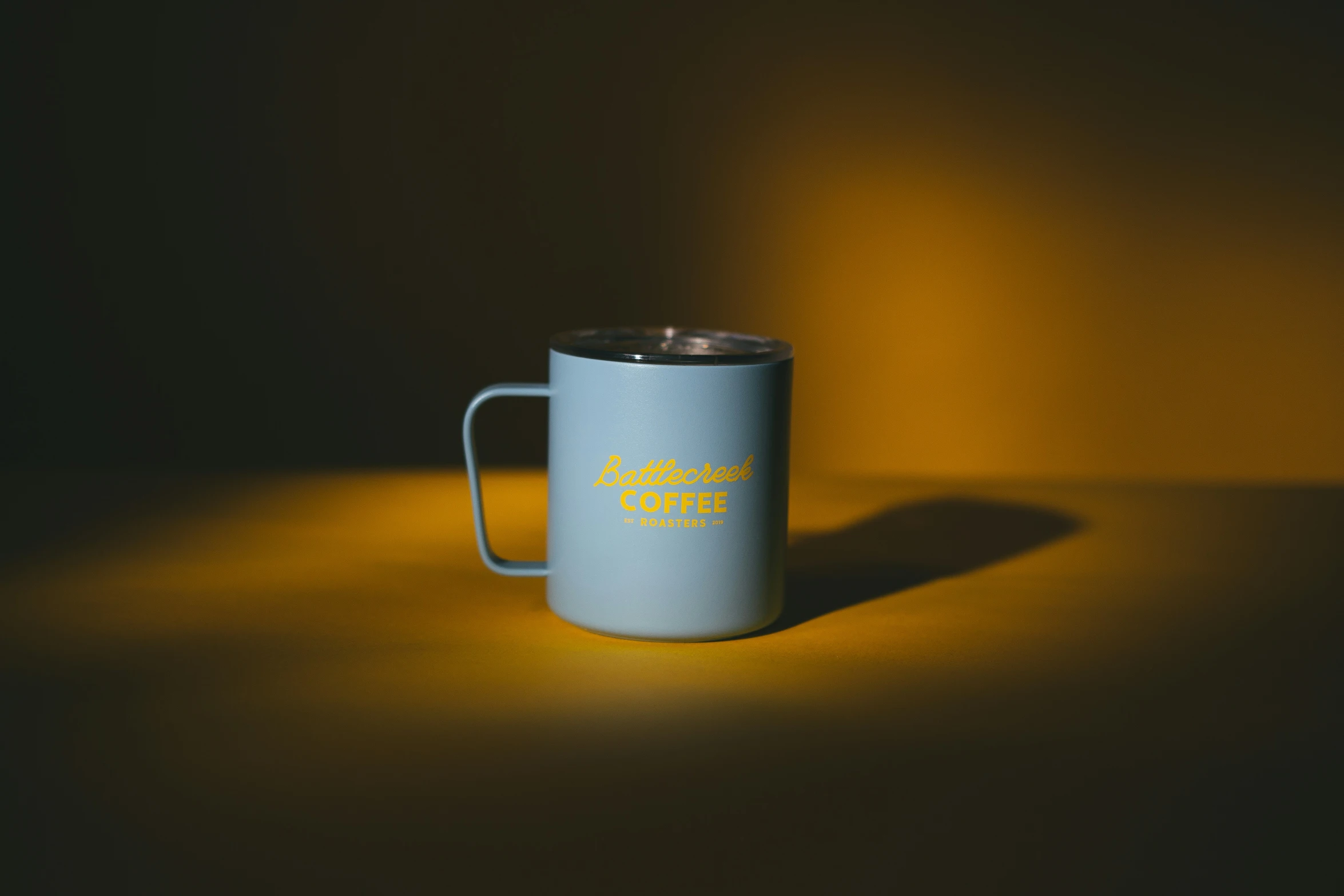 a coffee cup sitting on top of a yellow surface