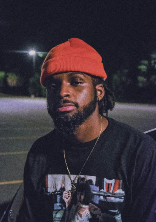 young man wearing a red cap standing in a parking lot