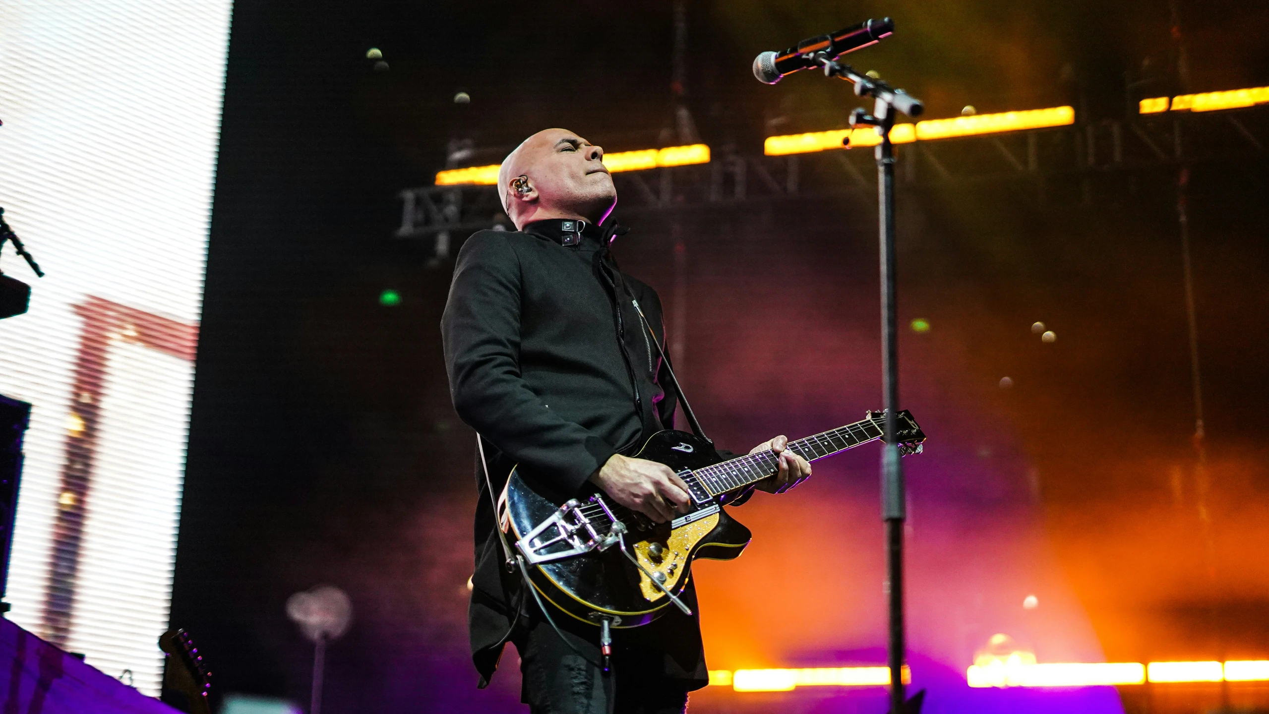 a man playing guitar on stage with his microphone