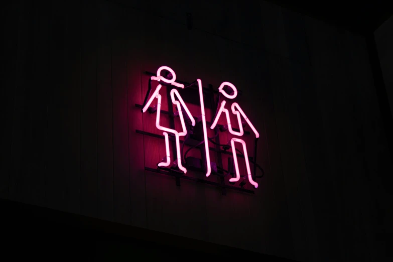 pink neon sign on the wall saying restroom