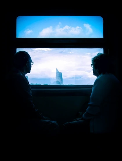 the two men are sitting in a room by a window